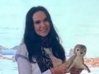 Lächelnde Frau mit einem Robben Kuscheltier